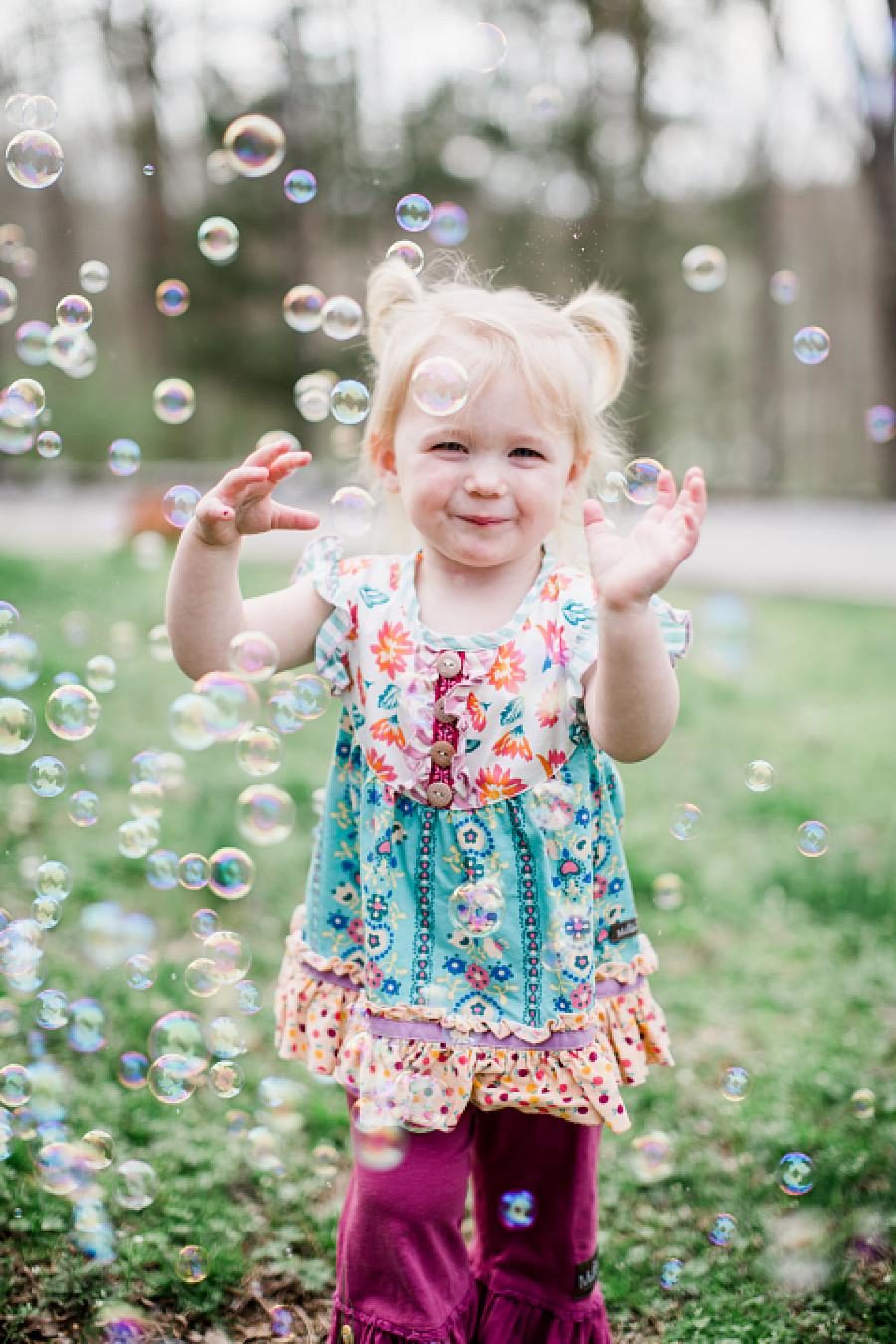 little girl in a cute outfit playing bubbles outside
