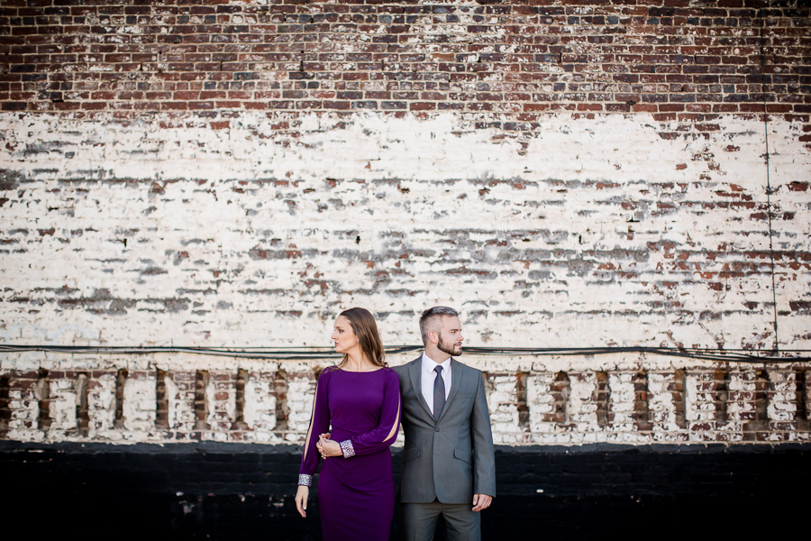In front of brick wall engagement photo by Knoxville Wedding Photographer, Amanda May Photos.