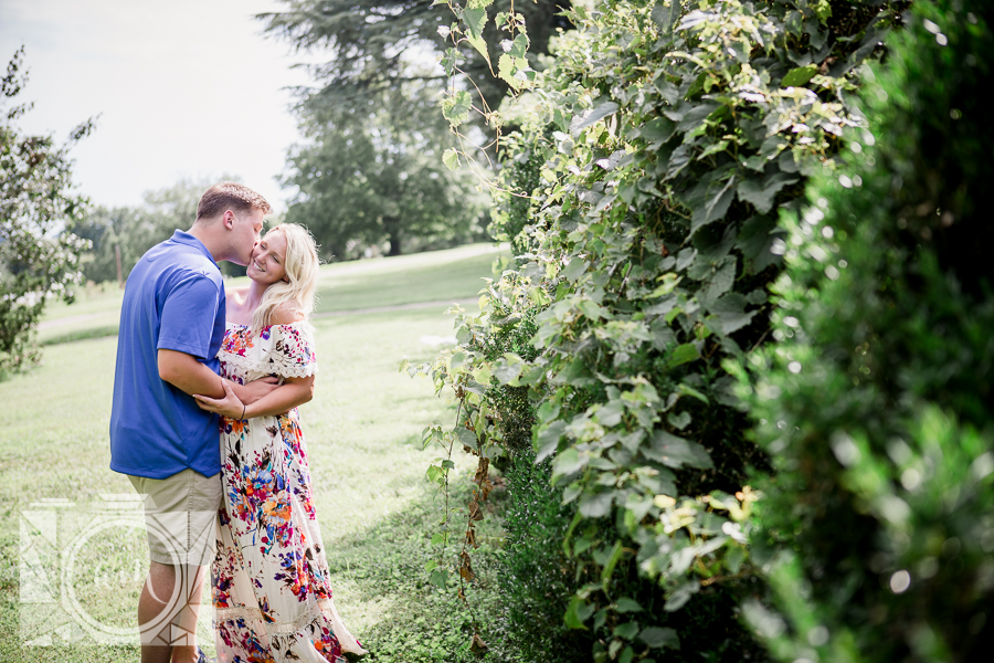 Kissing her cheek in floral dress engagement photo by Knoxville Wedding Photographer, Amanda May Photos.