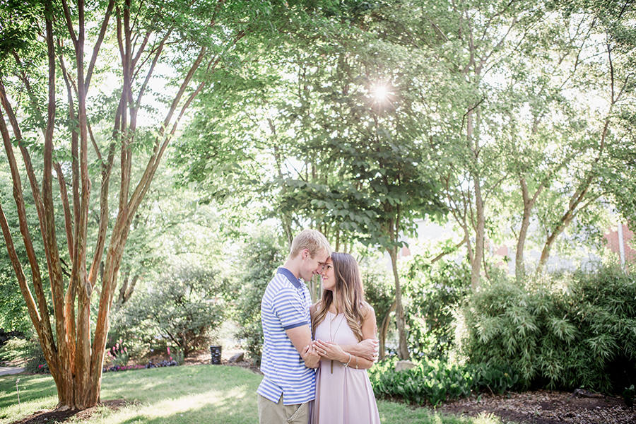 Foreheads together with sun light coming through trees engagement photo by Knoxville Wedding Photographer, Amanda May Photos.