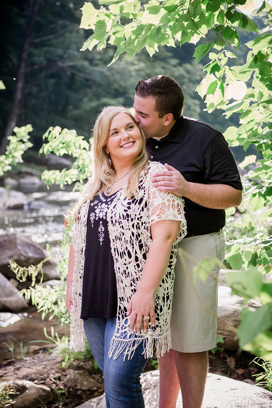 Her kisses her cheek from behind engagement photo by Knoxville Wedding Photographer, Amanda May Photos.