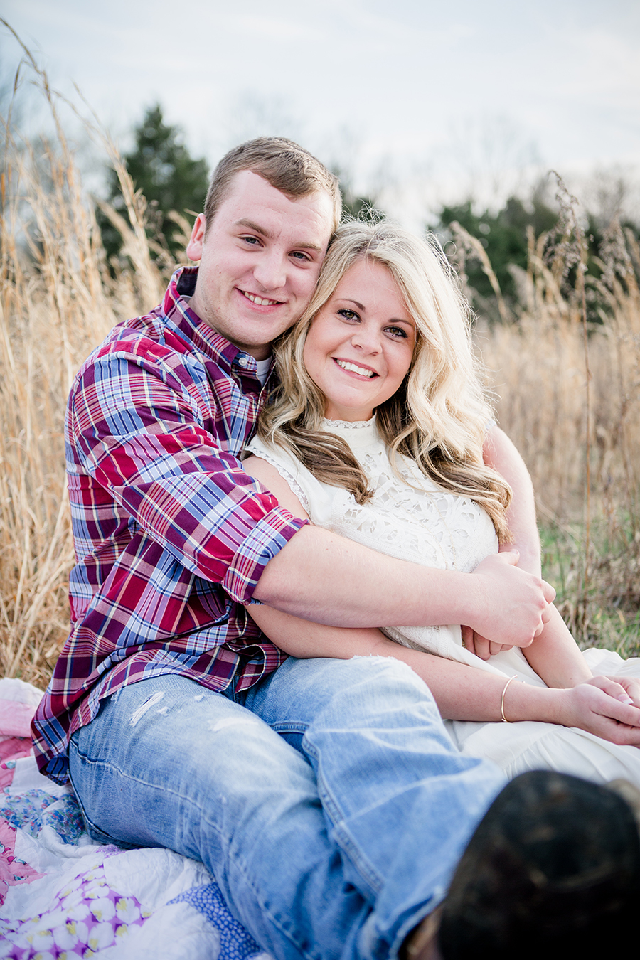 Sitting on a blanket leaning back against his chest engagement photo by Knoxville Wedding Photographer, Amanda May Photos.