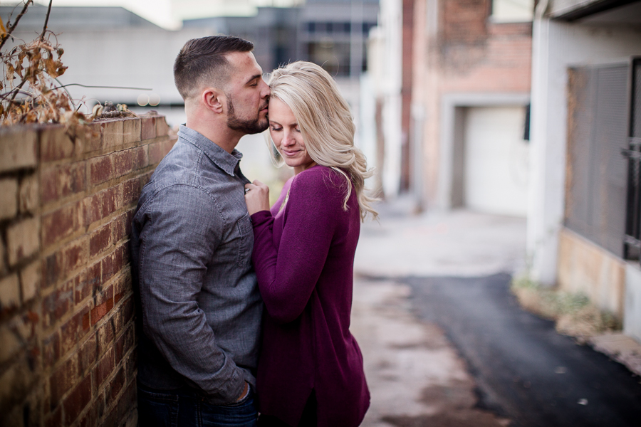 He kisses her forehead and she looks down over her shoulder engagement photo by Knoxville Wedding Photographer, Amanda May Photos.