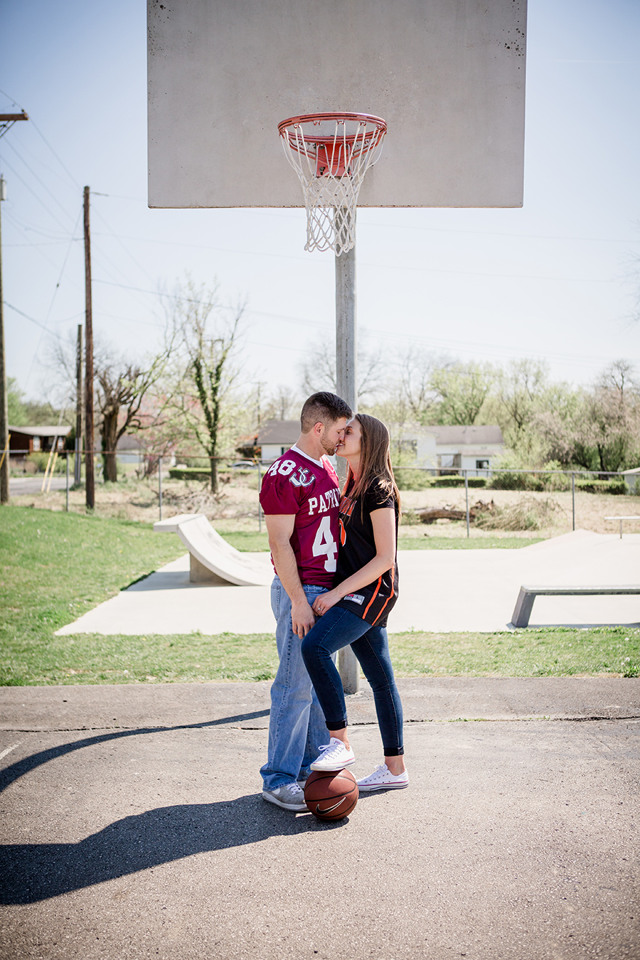 Kissing under basketball goal engagement photo by Knoxville Wedding Photographer, Amanda May Photos.