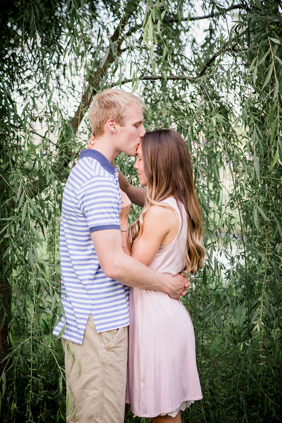 Kissing her forehead under weeping willow engagement photo by Knoxville Wedding Photographer, Amanda May Photos.