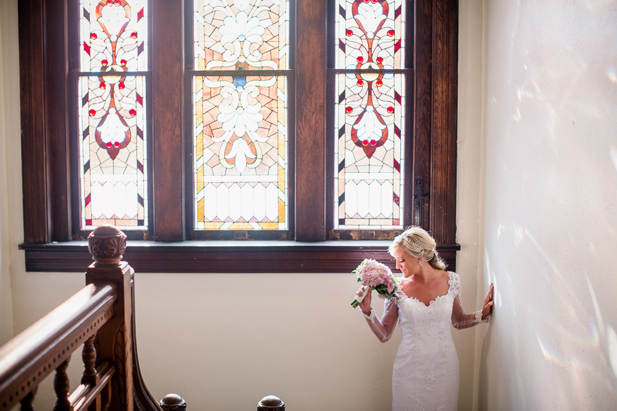 Smelling flowers with stain glass window at Historic Westwood by Knoxville Wedding Photographer, Amanda May Photos.