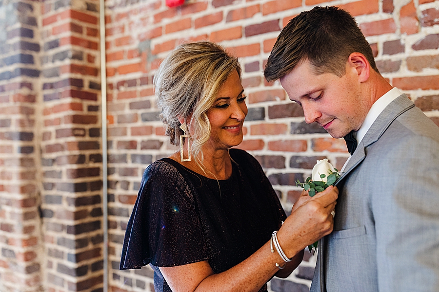 pinning the boutonniere at this black tie wedding