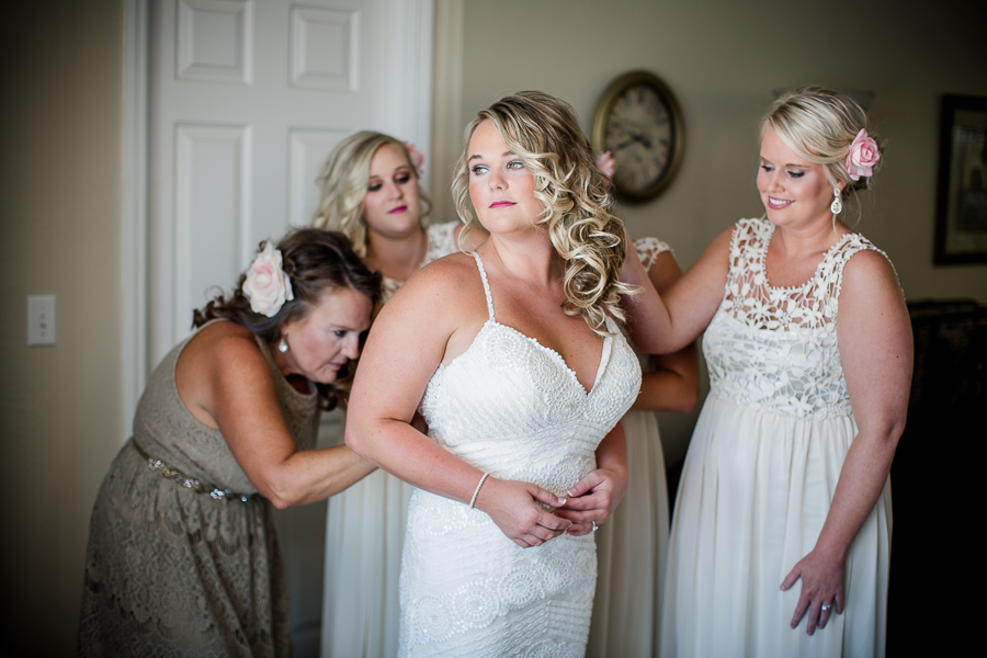 Bride getting help putting on wedding gown at this Daytona Beach Wedding by Destination Wedding Photographer, Amanda May Photos.