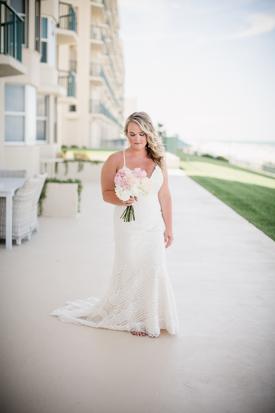 Bride looking at flowers in front of hotel at this Daytona Beach Wedding by Destination Wedding Photographer, Amanda May Photos.