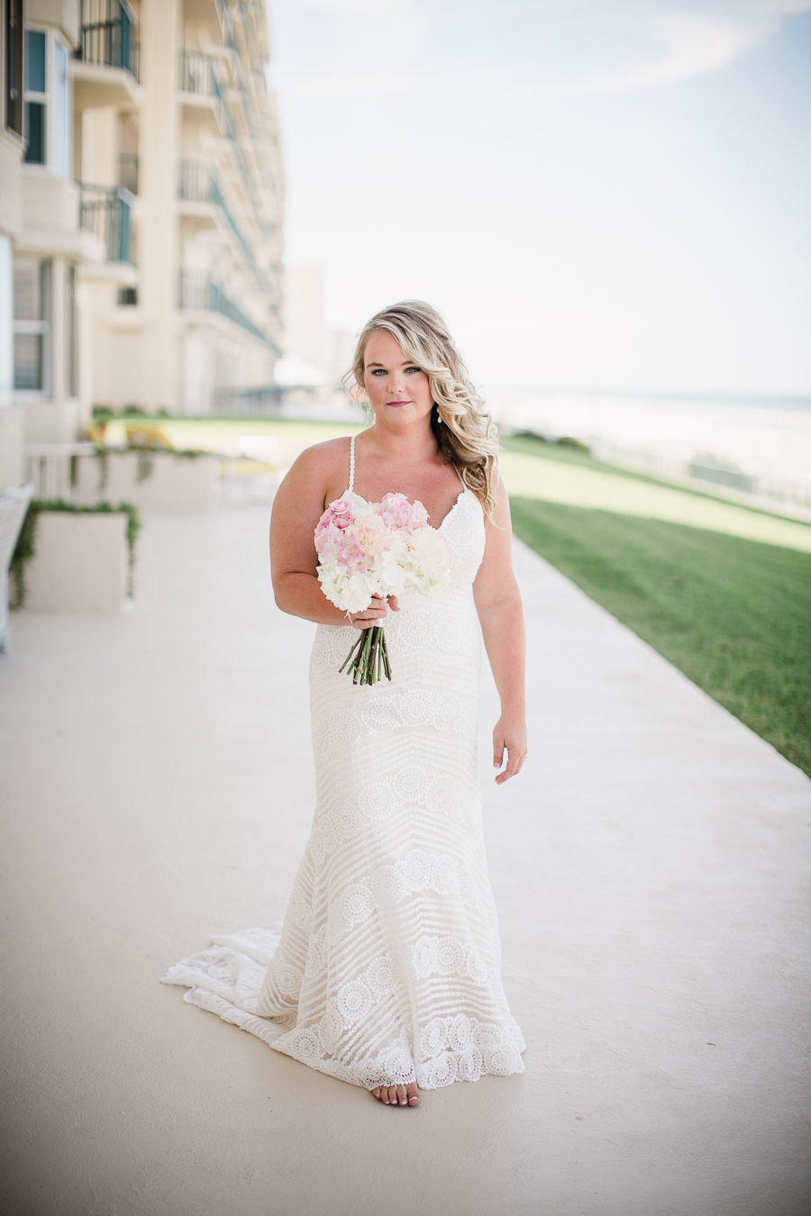 Bride holding flowers in front of hotel at this Daytona Beach Wedding by Destination Wedding Photographer, Amanda May Photos.