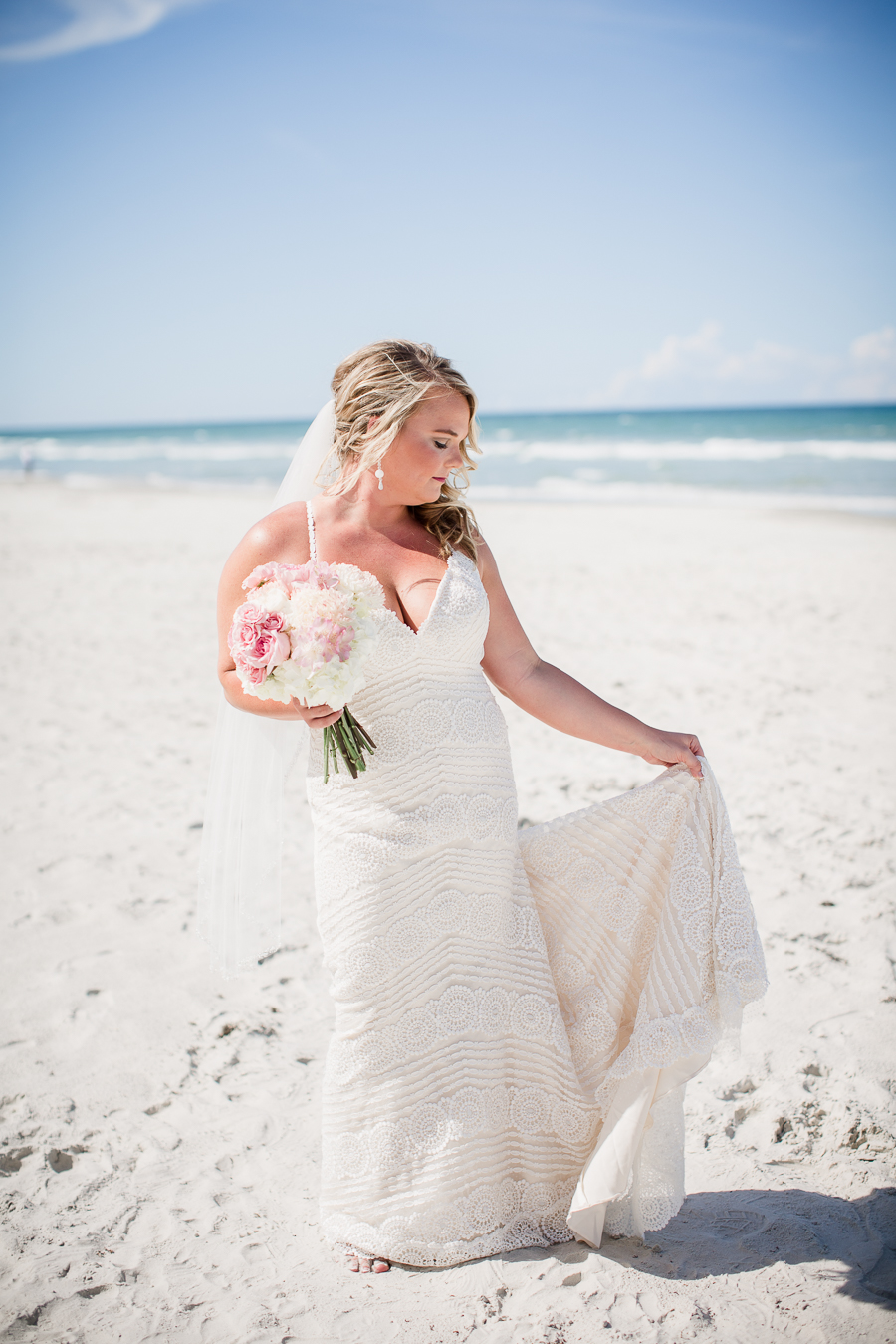 Bride holding dress on beach at this Daytona Beach Wedding by Destination Wedding Photographer, Amanda May Photos.