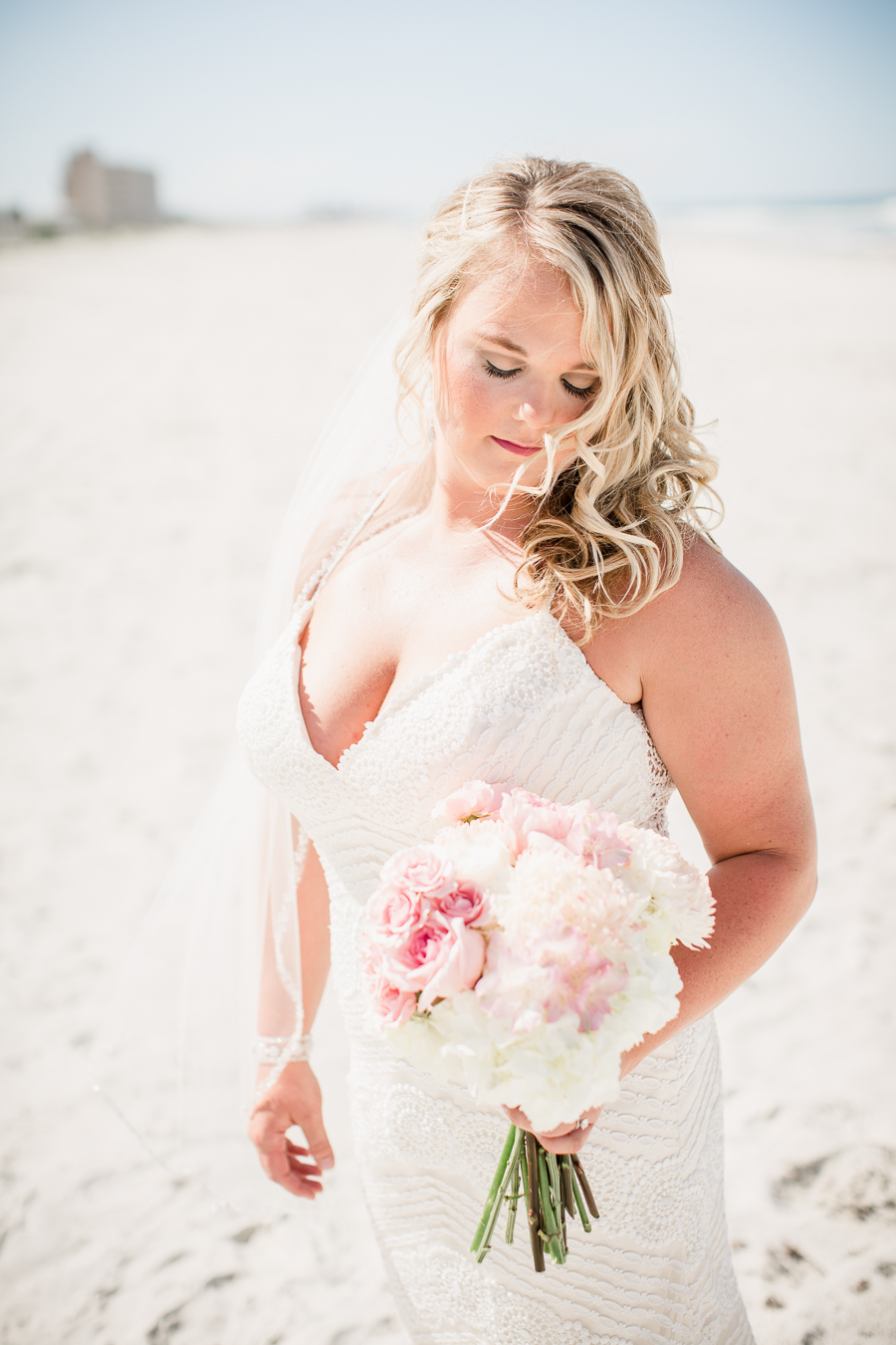 Bride looking at flowers on beach at this Daytona Beach Wedding by Destination Wedding Photographer, Amanda May Photos.