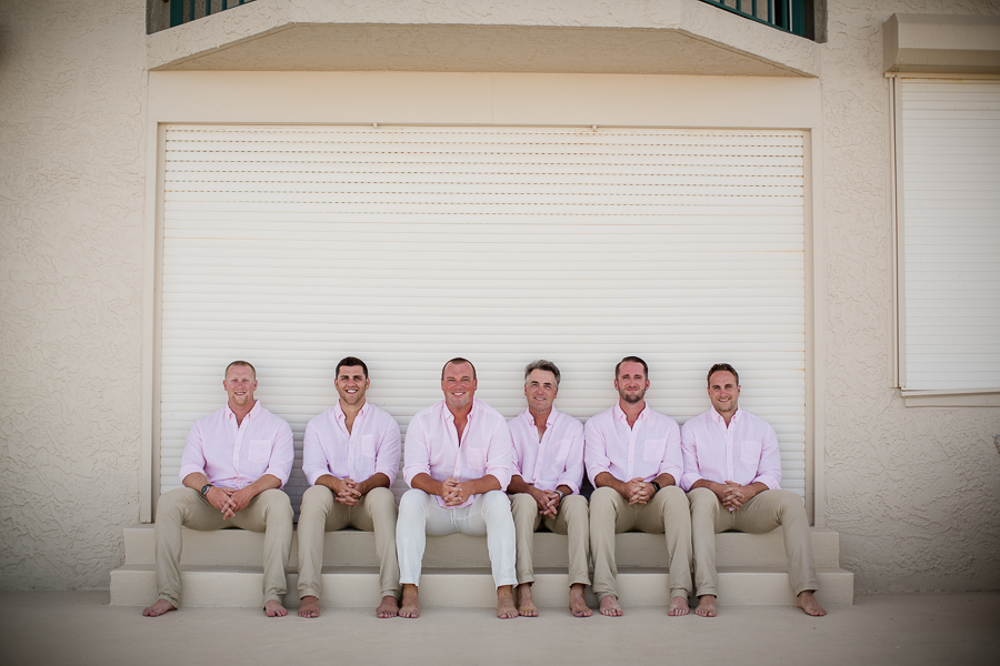 Groom with groomsmen sitting in front of wall at this Daytona Beach Wedding by Destination Wedding Photographer, Amanda May Photos.