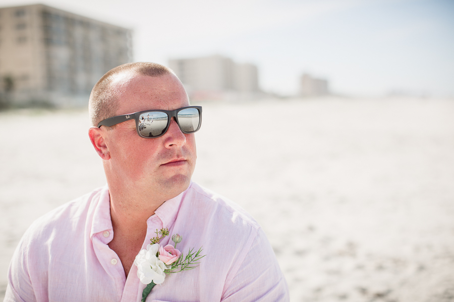 Groom wearing sunglasses looking out at beach at this Daytona Beach Wedding by Destination Wedding Photographer, Amanda May Photos.