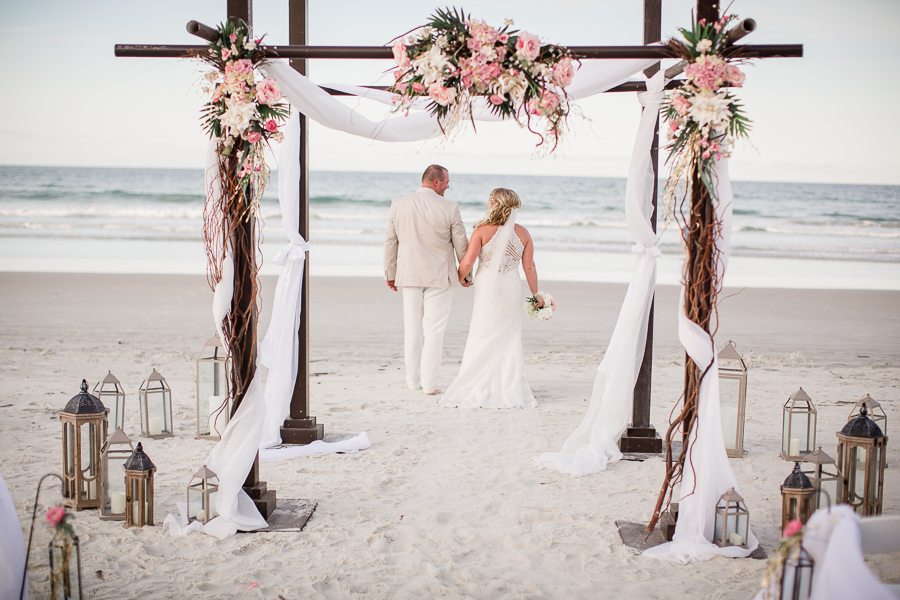 Bride and Groom walking to water under alter at this Daytona Beach Wedding by Destination Wedding Photographer, Amanda May Photos.