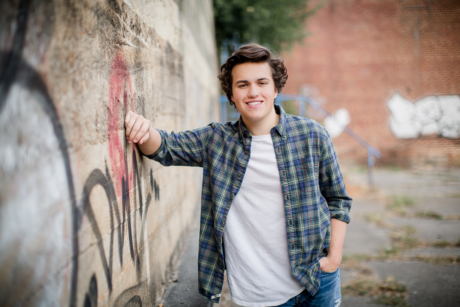 Leaning against graffiti wall at this Maryville, TN Senior session by Knoxville Wedding Photographer, Amanda May Photos.