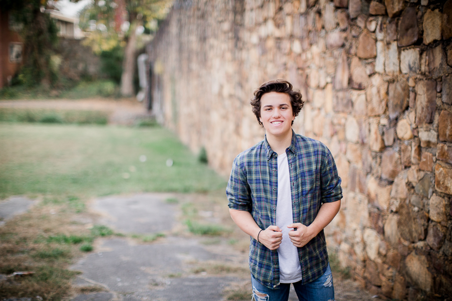 Hands holding plaid shirt in front of stone wall at this Maryville, TN Senior session by Knoxville Wedding Photographer, Amanda May Photos.