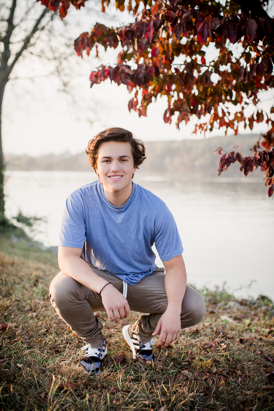 Squatting below a red tree at this Maryville, TN Senior session by Knoxville Wedding Photographer, Amanda May Photos.