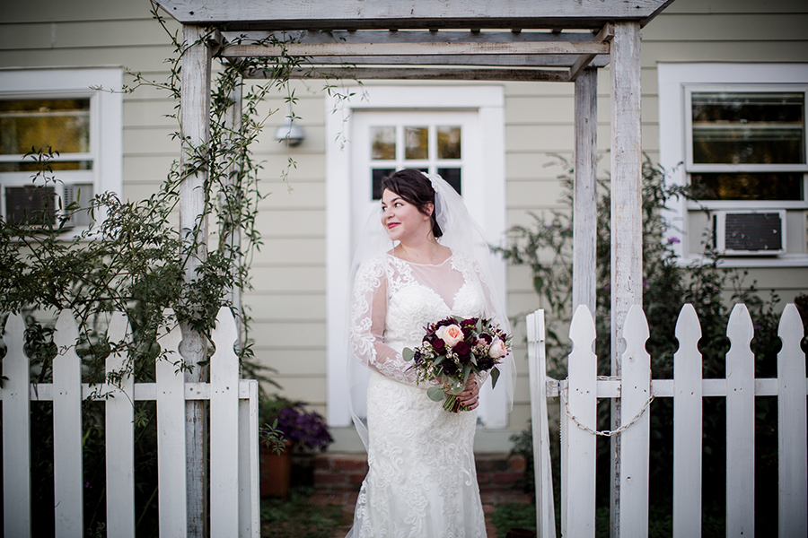 Looking back over her shoulder standing between a picket fence at this bridal session at The Barn at High Point Farms by Knoxville Wedding Photographer, Amanda May Photos.
