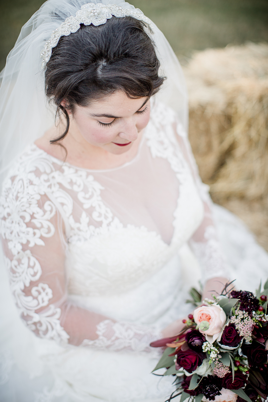 Looking down at her flowers while sitting on hay bales at this bridal session at The Barn at High Point Farms by Knoxville Wedding Photographer, Amanda May Photos.