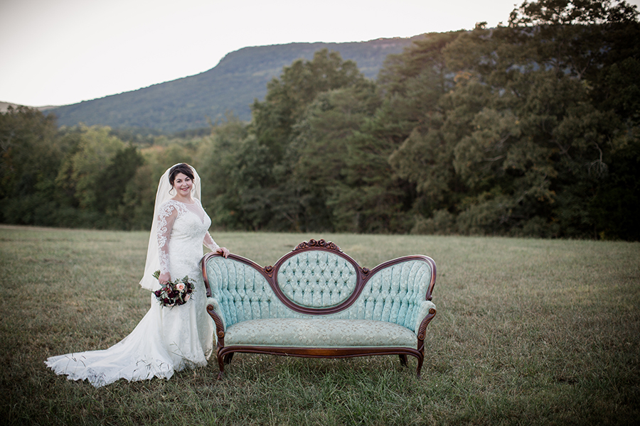 Standing with a vintage couch in a field at this bridal session at The Barn at High Point Farms by Knoxville Wedding Photographer, Amanda May Photos.