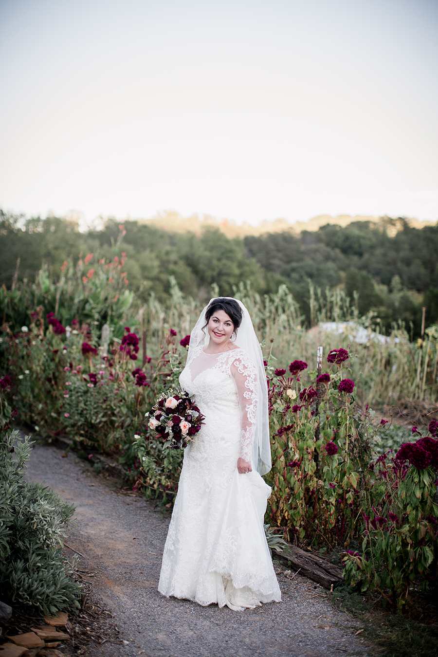 Standing in front of maroon wild flowers at this bridal session at The Barn at High Point Farms by Knoxville Wedding Photographer, Amanda May Photos.