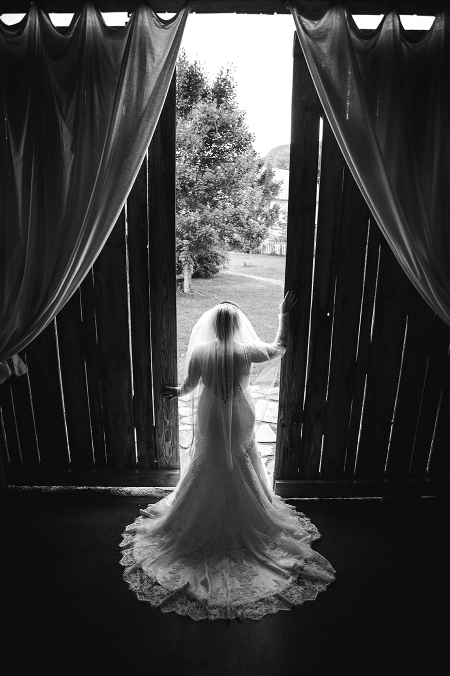 Black and white of the bride opening barn doors at this bridal session at The Barn at High Point Farms by Knoxville Wedding Photographer, Amanda May Photos.