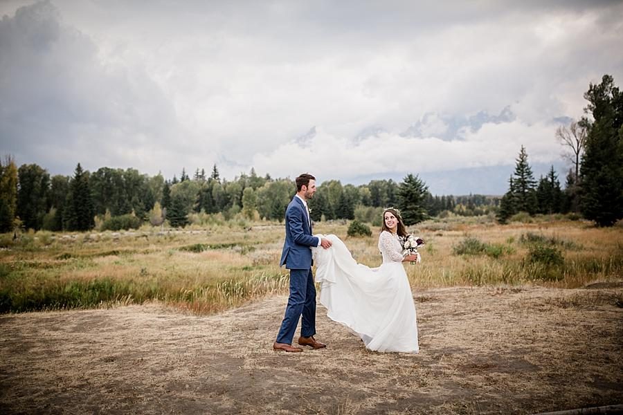 Walking while he holds her dress at this Grand Tetons Destination Wedding by Knoxville Wedding Photographer, Amanda May Photos.