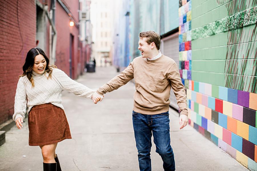 Couple holding hands in a painted alleyway