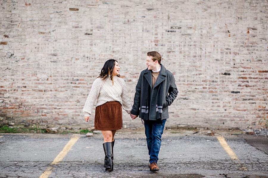 Couple holding hands in front of a brick wall