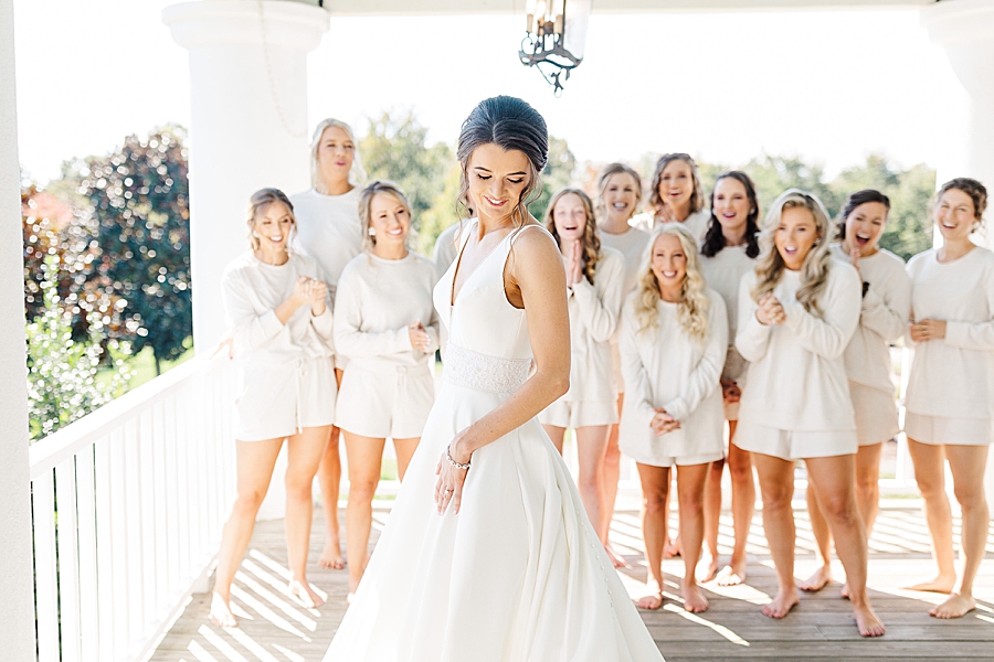 Bride showing dress to bridesmaids at this fall castleton farms wedding