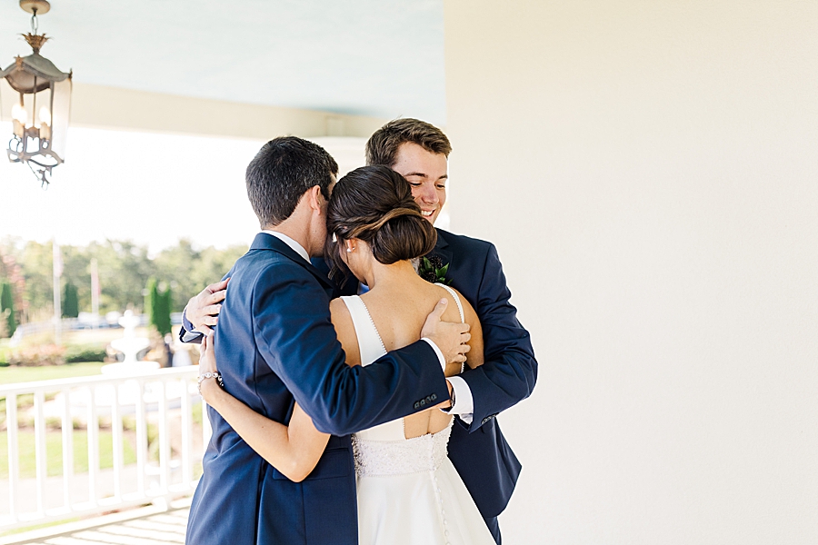 Bride hugging brothers at this fall castleton farms wedding