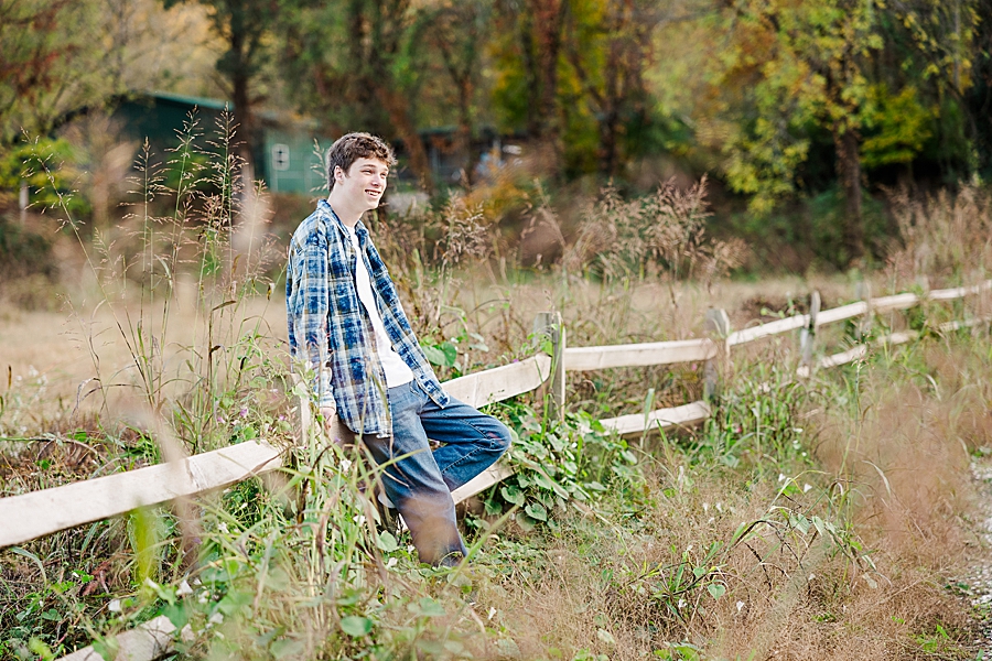 boy sitting on wooden fence at this forks of the river senior