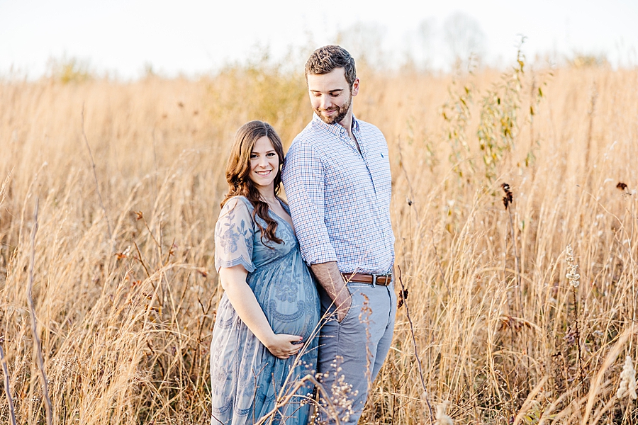 pregnant couple standing in tall grass