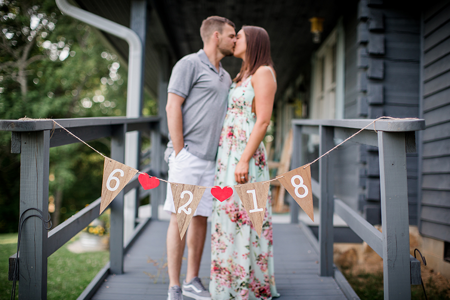 Kissing with wedding date banner in front at this Estate of Grace engagement session by Knoxville Wedding Photographer, Amanda May Photos.