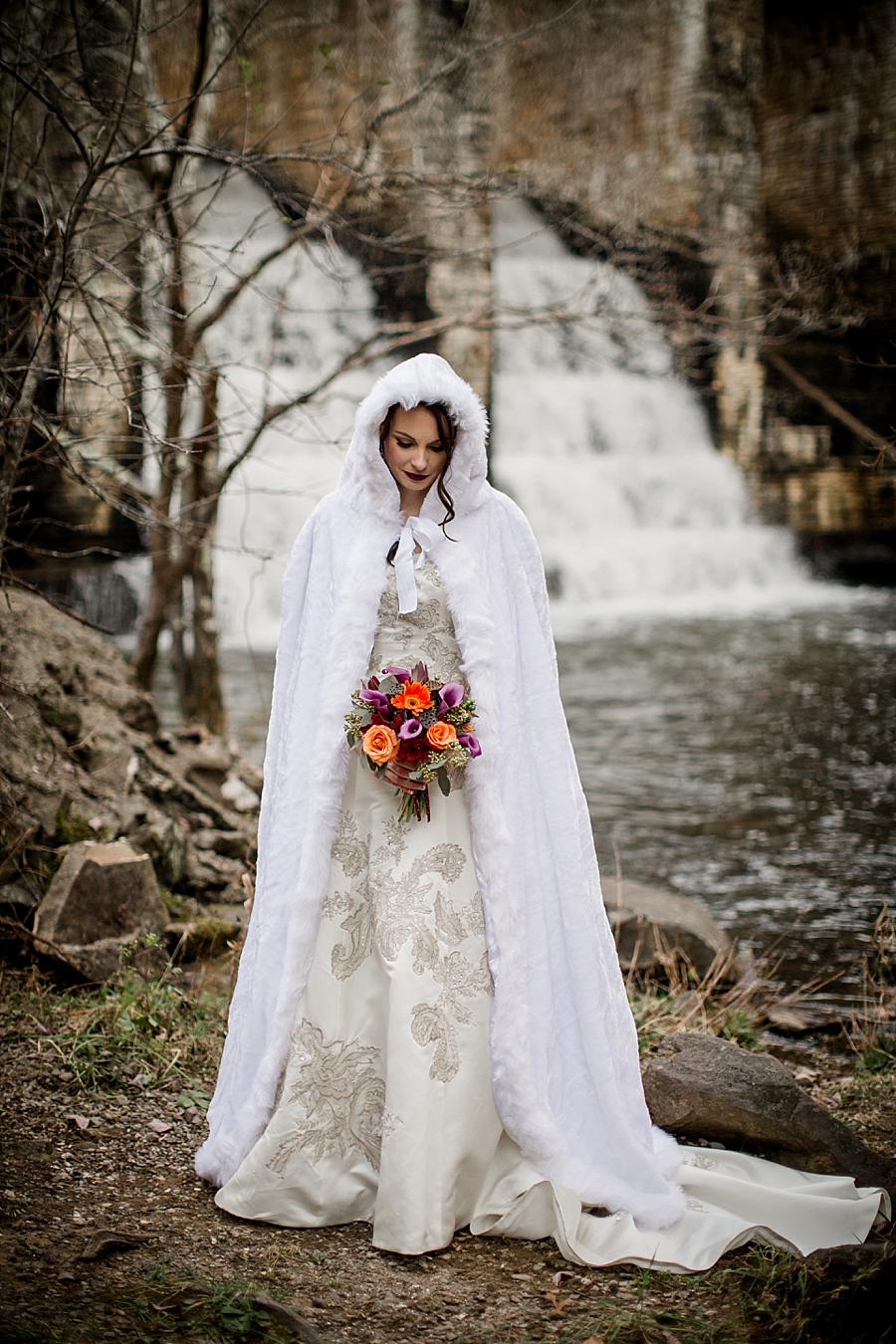 Looking down at her bouquet in front of waterfalls at this Cumberland Mountain State Park wedding by Knoxville Wedding Photographer, Amanda May Photos.
