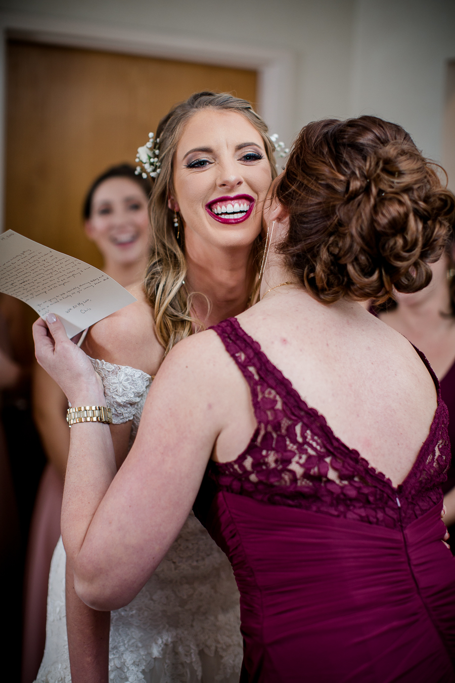 Sister and maid of honor kissing the bride on the cheek during this getting ready picture at this winter wedding at Knoxville Wedding Venue, Jackson Terminal, by Knoxville Wedding Photographer, Amanda May Photos.