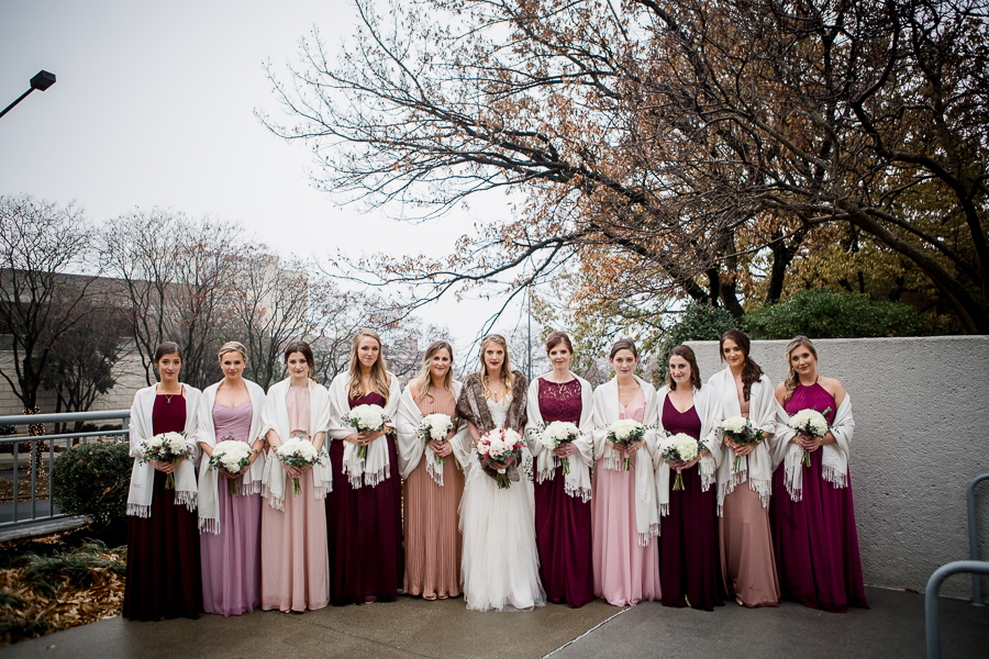 Standing super close together during the bride and bridesmaids pictures at this winter wedding at Knoxville Wedding Venue, Jackson Terminal, by Knoxville Wedding Photographer, Amanda May Photos.
