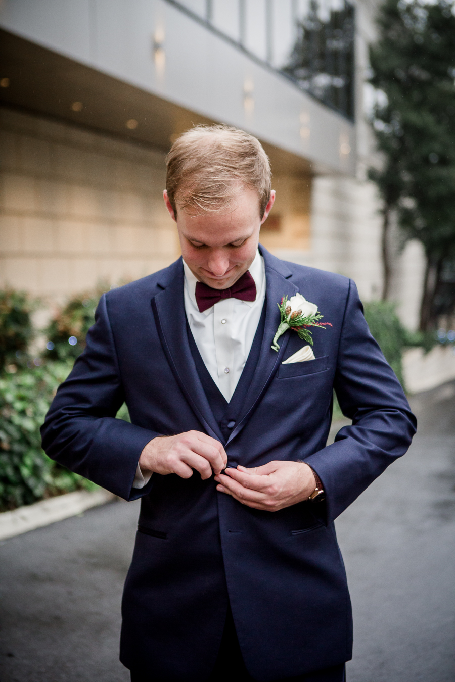 Buttoning his jacket during the groom and groomsmen pictures at this winter wedding at Knoxville Wedding Venue, Jackson Terminal, by Knoxville Wedding Photographer, Amanda May Photos.