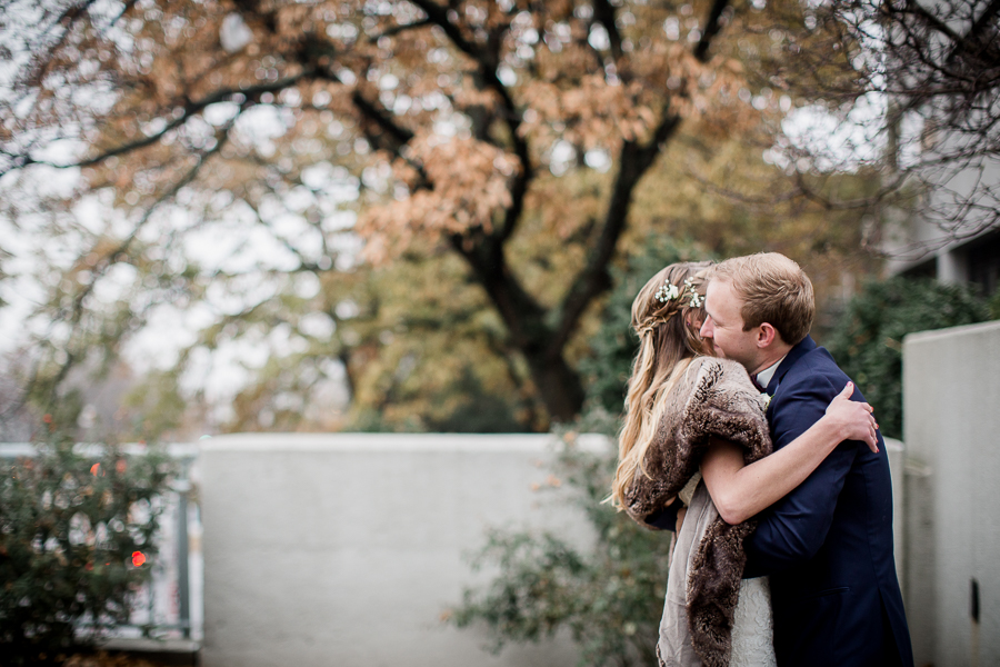 His arms wrapped around her waste during the first look pictures at this winter wedding at Knoxville Wedding Venue, Jackson Terminal, by Knoxville Wedding Photographer, Amanda May Photos.