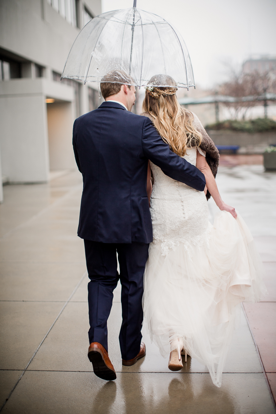 Groom escorting the bride under an umbrella during the bride and groom romantic portraits at this winter wedding at Knoxville Wedding Venue, Jackson Terminal, by Knoxville Wedding Photographer, Amanda May Photos.