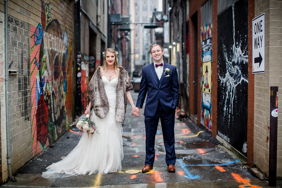 Hand in hand facing the camera during the bride and groom romantic portraits at this winter wedding at Knoxville Wedding Venue, Jackson Terminal, by Knoxville Wedding Photographer, Amanda May Photos.