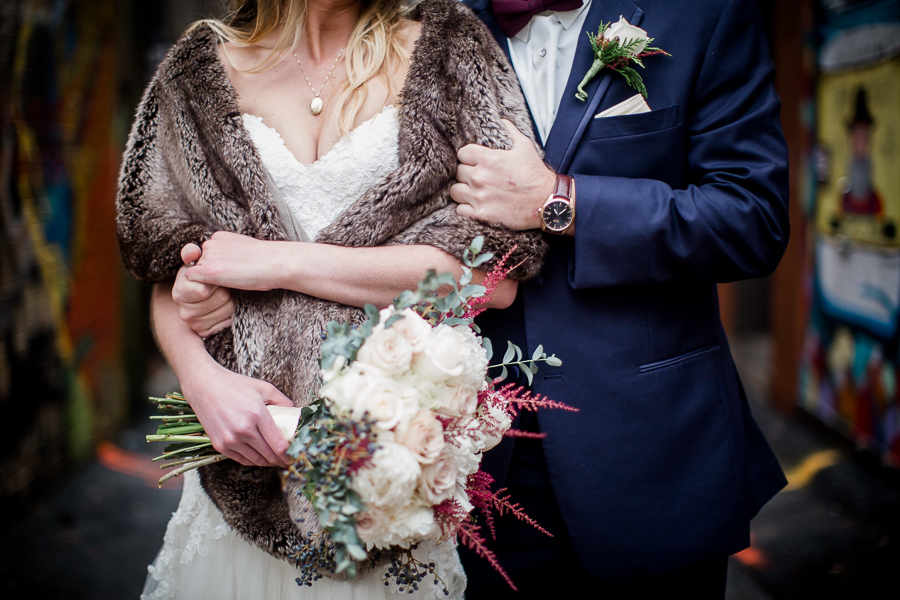 Arms wrapped all cuddly around each other during the bride and groom romantic portraits at this winter wedding at Knoxville Wedding Venue, Jackson Terminal, by Knoxville Wedding Photographer, Amanda May Photos.