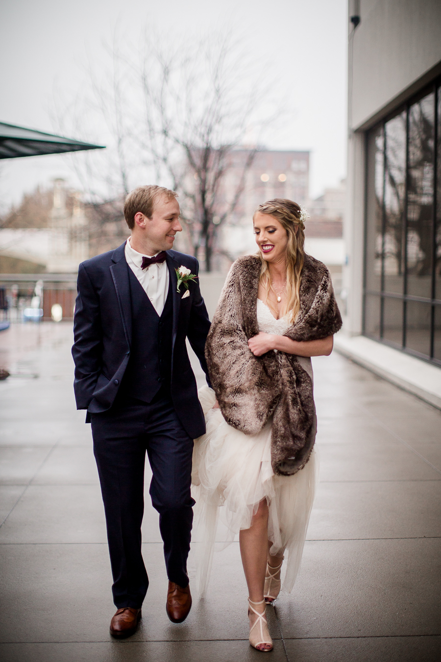 Walking together during the bride and groom romantic portraits at this winter wedding at Knoxville Wedding Venue, Jackson Terminal, by Knoxville Wedding Photographer, Amanda May Photos.