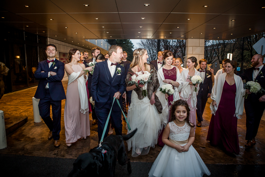 Walking under the awning of the Crown Plaza during the bridal party pictures at this winter wedding at Knoxville Wedding Venue, Jackson Terminal, by Knoxville Wedding Photographer, Amanda May Photos.