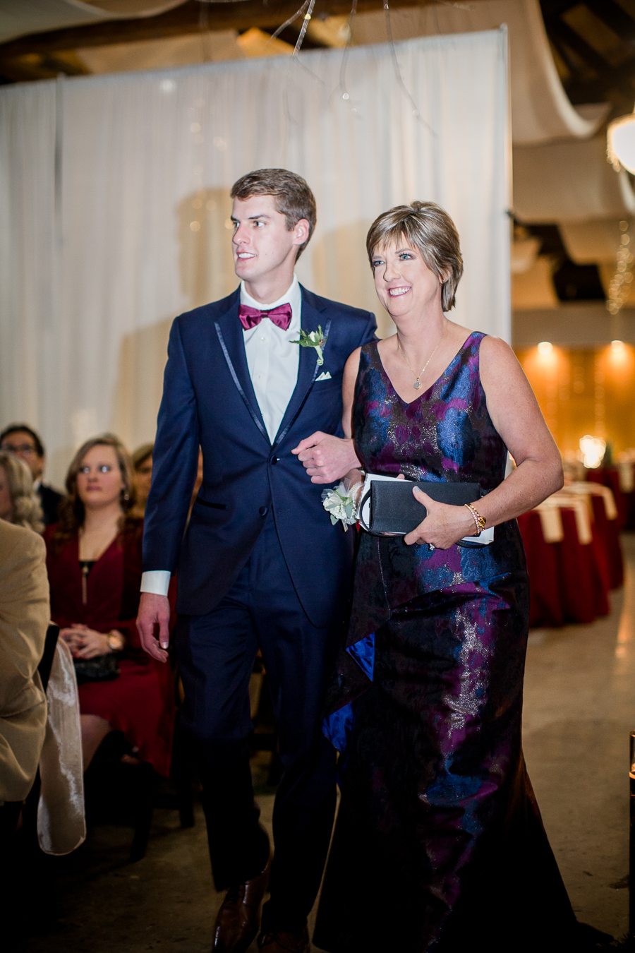 Mother of the bride being escorted down the aisle by her son during the ceremony pictures at this winter wedding at Knoxville Wedding Venue, Jackson Terminal, by Knoxville Wedding Photographer, Amanda May Photos.