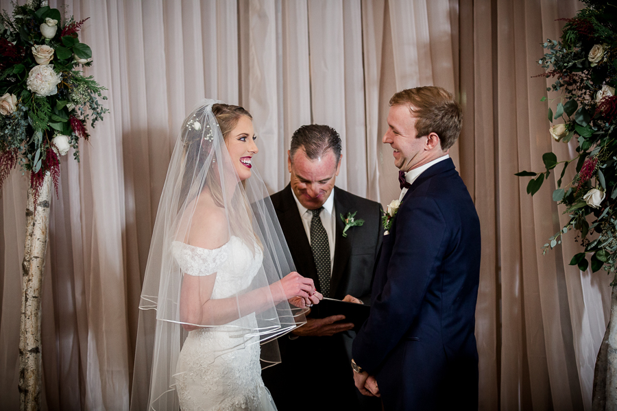 Bride laughs when she doesn't repeat the vows correctly during the ceremony pictures at this winter wedding at Knoxville Wedding Venue, Jackson Terminal, by Knoxville Wedding Photographer, Amanda May Photos.