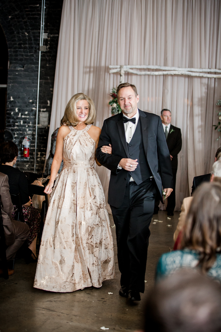 Mother and father of the groom walking down the aisle during the ceremony pictures at this winter wedding at Knoxville Wedding Venue, Jackson Terminal, by Knoxville Wedding Photographer, Amanda May Photos.
