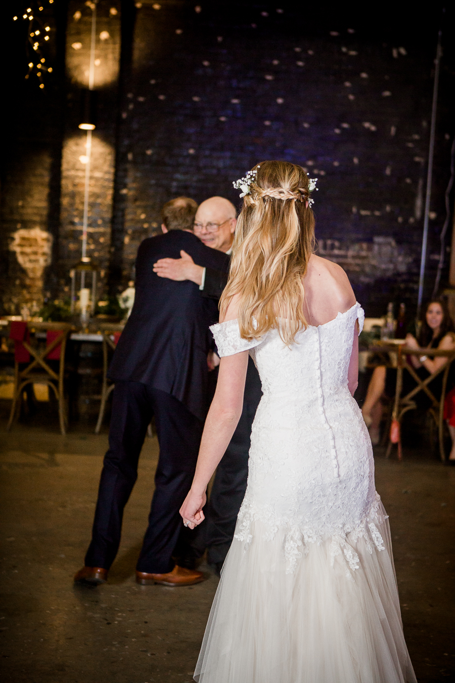 Groom hugs the father of the bride during the reception pictures at this winter wedding at Knoxville Wedding Venue, Jackson Terminal, by Knoxville Wedding Photographer, Amanda May Photos.