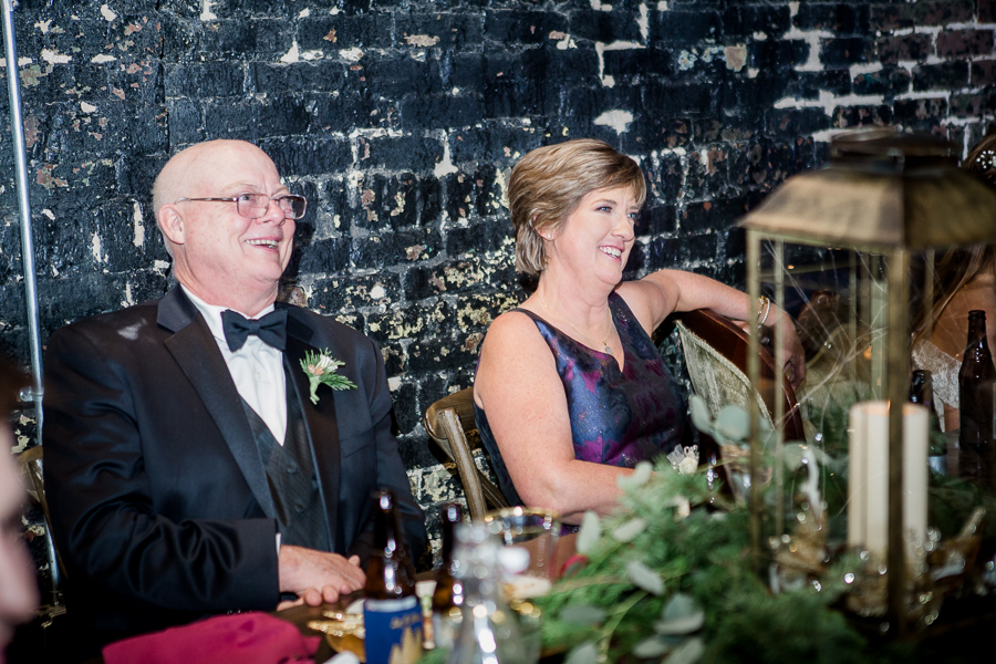 Parents of the bride laugh during toasts during the reception pictures at this winter wedding at Knoxville Wedding Venue, Jackson Terminal, by Knoxville Wedding Photographer, Amanda May Photos.
